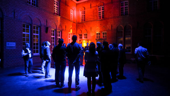 Un groupe de personnes discute à l'extérieur d'un bâtiment magnifiquement mis en lumière à Turnhout, en Belgique, dans le cadre d'un atelier organisé par Philips