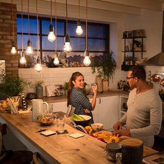 Couple discutant sous des ampoules LED Vintage Philips suspendues au plafond pour créer une lumière chaleureuse