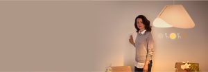 "Femme réglant un variateur connecté, contrôlant l'ambiance chaleureuse de l'éclairage LED dans un espace de vie contemporain au décor minimaliste"
