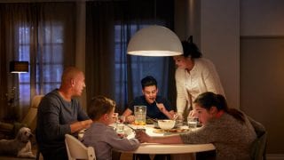 Une grande suspension à LED illumine la table du dîner familial, créant une ambiance chaleureuse pour les repas du soir et présentant des solutions d'éclairage au plafond écoénergétiques pour les maisons modernes
