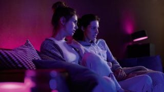 Les lampes LED connectées Philips Hue créent une ambiance violette et rose vibrante dans le salon, présentant un éclairage d'ambiance personnalisable pour les soirées cinéma et la détente dans les maisons modernes.