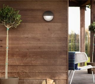 L'applique murale extérieure à LED moderne illumine l'extérieur en bois rustique, présentant des solutions d'éclairage écoénergétiques et résistantes aux intempéries pour les façades et les porches de maisons contemporaines.