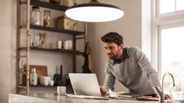un homme travaillant à la maison sous un luminaire connecté