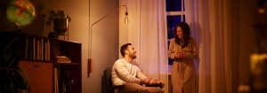 "Lampadaire à bulbe LED de style vintage créant une ambiance chaleureuse pour la conversation en soirée en couple, mettant en valeur un éclairage d'ambiance économe en énergie dans un salon confortable."