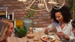 "Cuisine moderne avec des suspensions LED de style vintage illuminant deux femmes en train de dîner, créant une atmosphère chaleureuse et accueillante. »
